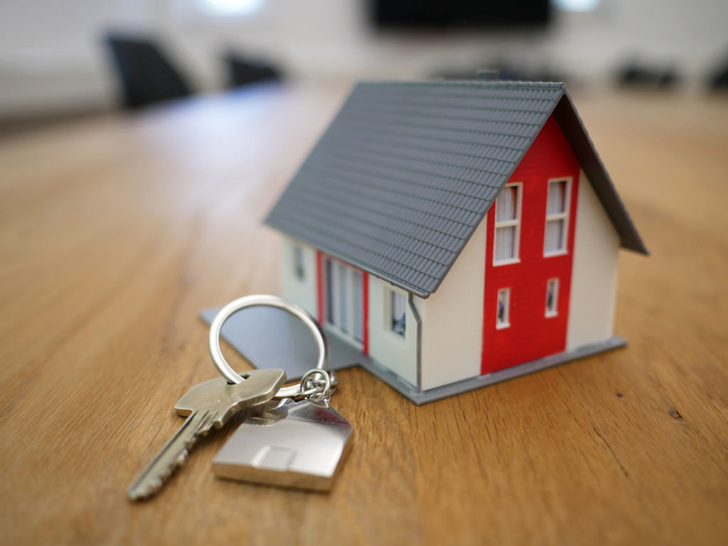A decorative house with a key in front of it lying on a table.