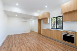 A light brown parquet floor in a kitchen with light brown cabinets and white walls.